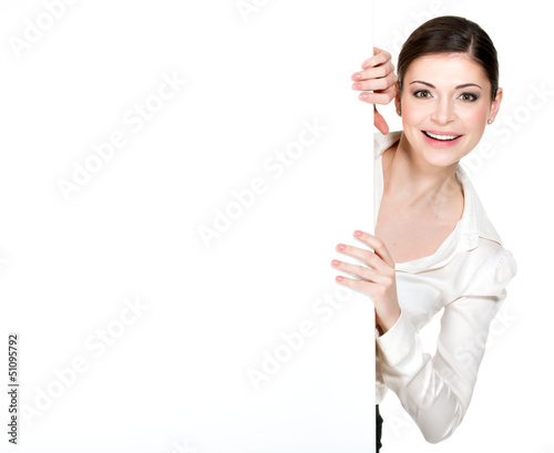 Photo: Young smiling woman looking from white blank banner Young smiling woman looking from white blank banner