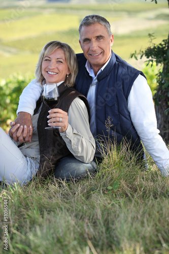 Photo: couple drinking wine in their vineyard couple drinking wine in their vineyard
