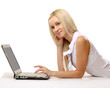 Portrait of a woman lying on the floor and working on a laptop.