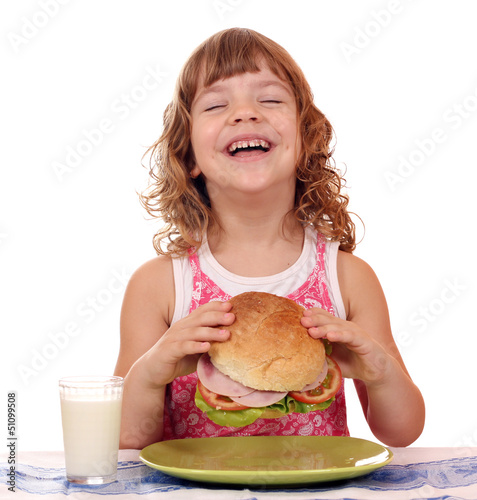 Photo: happy little girl eat big sandwich breakfast time happy little girl eat big sandwich breakfast time