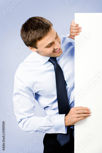 Photo: Business man showing blank signboard, on violet Business man showing blank signboard, on violet