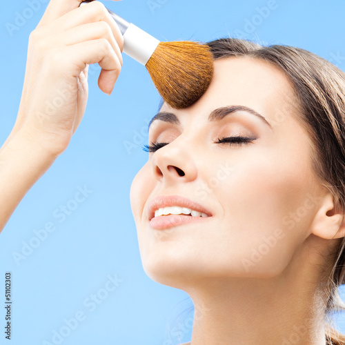 Photo: Woman with cosmetics brush, on blue Woman with cosmetics brush, on blue