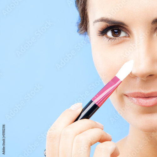 Photo: Woman with cosmetics brush, on blue Woman with cosmetics brush, on blue