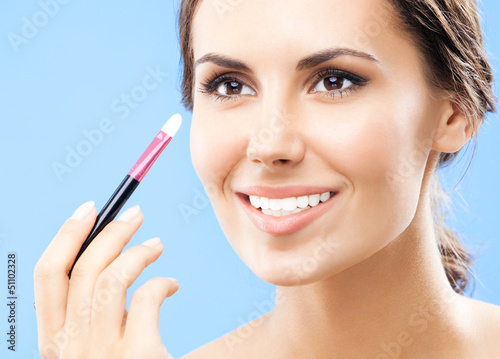 Photo: Woman with cosmetics brush, on blue Woman with cosmetics brush, on blue