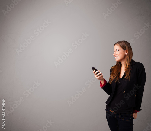 Photo: young lady standing and holding a phone with copy space young lady standing and holding a phone with copy space