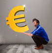 Good-looking boy holding a big 3d gold euro sign