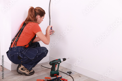 Photo: young woman installing electricity in a house young woman installing electricity in a house