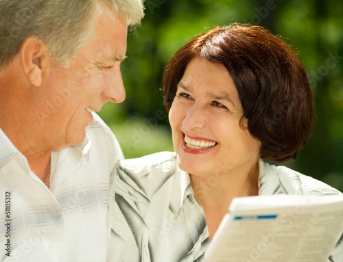Photo: Happy senior couple reading outdoors Happy senior couple reading outdoors