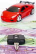 Black key on euro banknotes and red sports car background