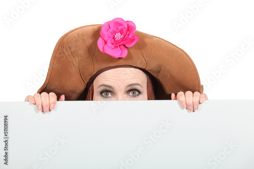 Photo: Woman hiding wearing a big brown hat Woman hiding wearing a big brown hat