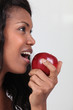 Woman taking a large bite out of a red apple
