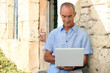 man using computer outside a lovely stone building