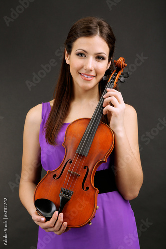 Photo: Beautiful young girl with violin on grey background Beautiful young girl with violin on grey background