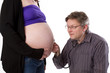 Father examines belly of expecting woman