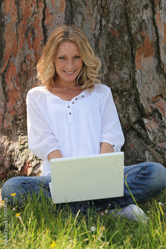 Photo: Woman on laptop under tree Woman on laptop under tree