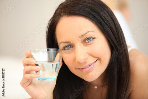Photo: Brunette laying on bed with glass of water Brunette laying on bed with glass of water