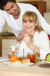 Woman eating breakfast while her affectionate boyfriend