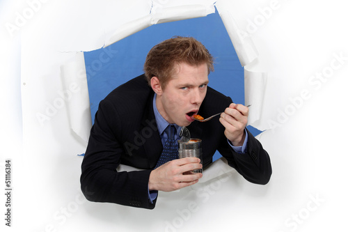 Photo: Businessman eating out of tin can Businessman eating out of tin can