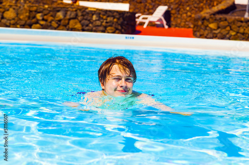 Photo: cute handsome teenage boy swims in the pool cute handsome teenage boy swims in the pool