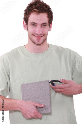 Photo: young man holding a tile and a nipper young man holding a tile and a nipper
