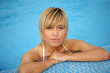 Blond woman resting by the edge of the swimming pool