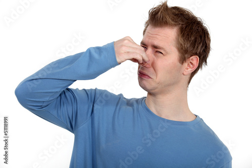 Photo: Man holding his nose against a bad smell Man holding his nose against a bad smell