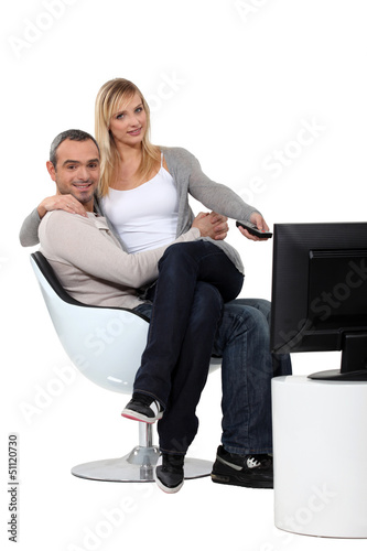 Photo: Couple sitting in a chair watching television Couple sitting in a chair watching television