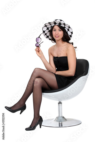 Photo: Brunette sat in chair with sunglasses and hat Brunette sat in chair with sunglasses and hat