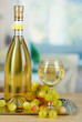 White wine in glass with bottle on salver on room background