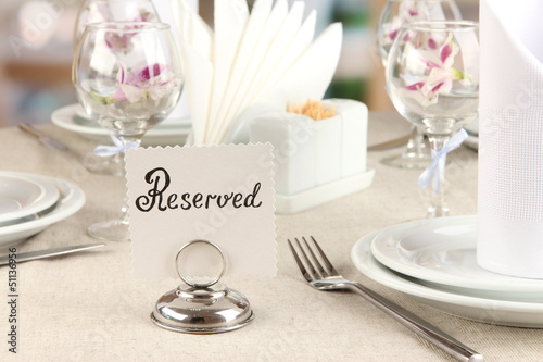 Photo: Reserved sign on restaurant table with empty dishes and glasses Reserved sign on restaurant table with empty dishes and glasses