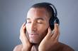 Afro man listening to music on DJ headphones with eyes closed