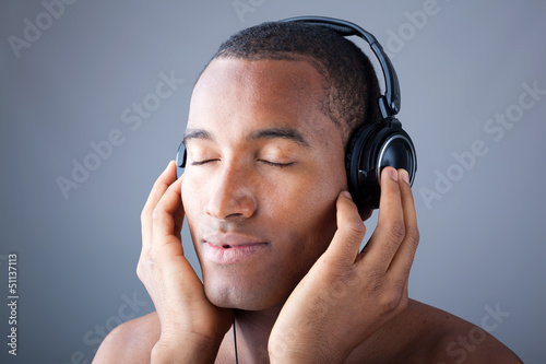Photo: Afro man listening to music on DJ headphones with eyes closed Afro man listening to music on DJ headphones with eyes closed