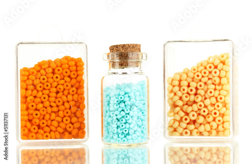 Photo: Colorful beads heap in boxes and glass bottle isolated on white Colorful beads heap in boxes and glass bottle isolated on white