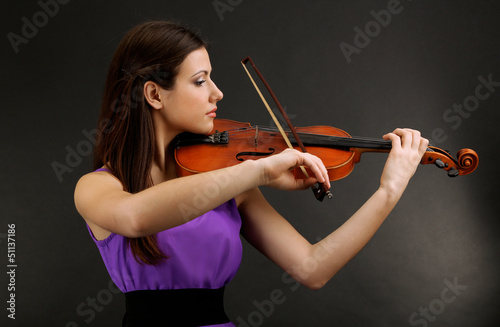 Photo: Beautiful young girl with violin on grey background Beautiful young girl with violin on grey background
