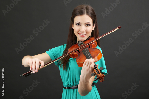 Photo: Beautiful young girl with violin on grey background Beautiful young girl with violin on grey background