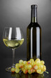 White wine glass and bottle of wine on grey background