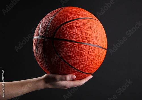 Photo: Basketball in woman hand on black background Basketball in woman hand on black background