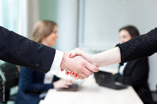 Photo: Business handshake and business people at the office Business handshake and business people at the office