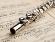 Photo: Silver flute on an ancient musical background Silver flute on an ancient musical background