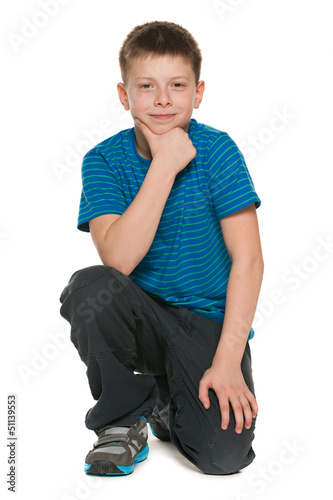 Photo: Pensive boy in blue shirt sits on the floor Pensive boy in blue shirt sits on the floor