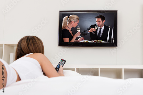 Photo: Young Woman Lying On Her Bed And Watching Television Young Woman Lying On Her Bed And Watching Television
