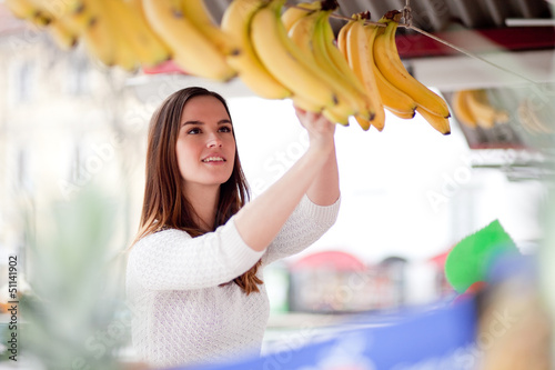 Photo: Young woman buying bananas at the market Young woman buying bananas at the market