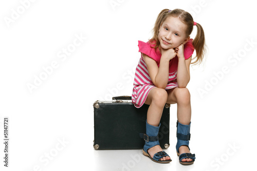 Photo: Little girl with sitting on the old fashioned suitcase Little girl with sitting on the old fashioned suitcase