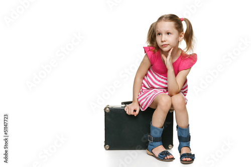 Photo: Little girl with sitting on the old fashioned suitcase Little girl with sitting on the old fashioned suitcase