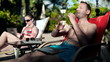 Young couple lying on sunbed using technology