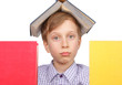 Little blond boy with a book on his head looking tired from behi
