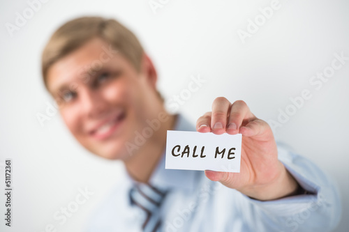 Photo: Handsome businessman showing "call me" text on a business card Handsome businessman showing "call me" text on a business card