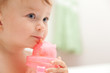 The little blue-eyed baby girl drinks juice from a bottle