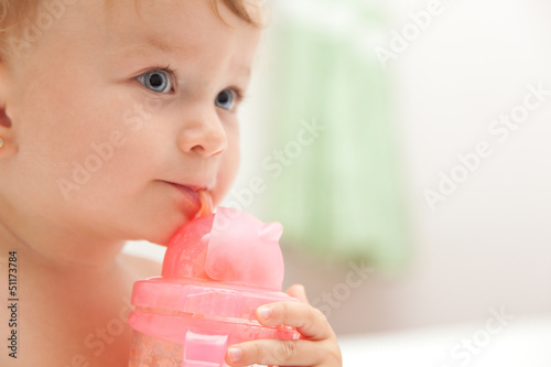 Photo: The little blue-eyed baby girl drinks juice from a bottle The little blue-eyed baby girl drinks juice from a bottle