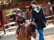 Mother riding her son on a pony 